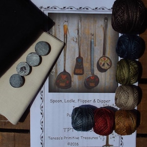 May include: A cross stitch kit featuring a set of four kitchen utensils: a spoon, ladle, flipper, and dipper. The kit includes six skeins of embroidery floss in various shades of brown, blue, green, and beige. The kit also includes a piece of linen fabric and a set of transfer needles.