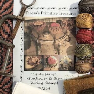 May include: A set of embroidery floss in shades of brown, gold, green, and red. The floss is arranged in a vertical row. The floss is labeled "Strawberry, Sunflower & Bee Sewing Clamps #N269".
