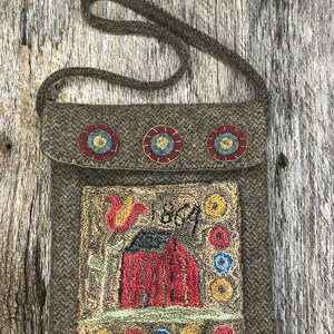 May include: An olive green wool shoulder bag with a flap. It has three embroidered floral designs and a central panel showing a red building, a tulip, and the year "1864". The bag is handmade.