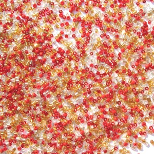May include: A close-up image of a large quantity of small, round, glass beads. The beads are a mix of red and gold colors.
