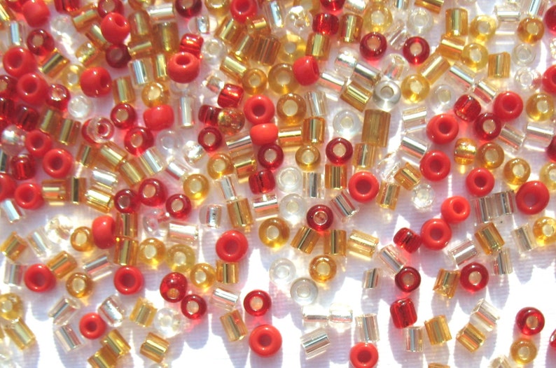 May include: A mix of red, gold, and clear glass beads. The beads are small and round, and they are perfect for jewelry making or other craft projects.