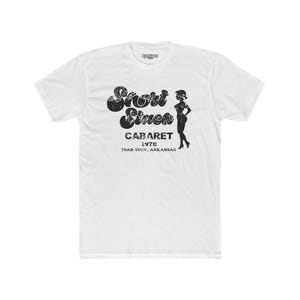 May include: White t-shirt with a black graphic print of a cabaret called "Short Stack" with the text "Cabaret 1978 Toad Suck, Arkansas".