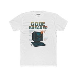 May include: White t-shirt with a distressed graphic featuring a skull inside a computer monitor, a keyboard, and the words "CODE BREAKER." Binary code and programming terms are also displayed. The shirt has a crew neck.