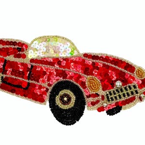 May include: A red classic car applique, embellished with sequins and beads. The car features black wheels, gold accents, and a light-colored windshield. This decorative applique is suitable for various craft projects.