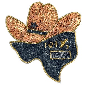 May include: A sequined patch in the shape of Texas, featuring a cowboy hat. The hat is copper-colored, and the Texas outline is black. The patch has the word "TEXAS" and "101%" embroidered on it.