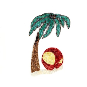 May include: A sequined applique featuring a palm tree and a beach ball. The palm tree has a brown trunk and teal green fronds. The beach ball is red and yellow. The applique is on a white background.