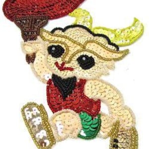 May include: A sequined appliqué of a cartoon figure running and holding a torch. The figure is wearing a red and black outfit with green shorts. The torch is red and brown. The figure has yellow horns and a yellow and white beard.