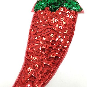 May include: Red and green sequined chili pepper applique. The chili pepper is made of red sequins and has a green sequined stem and leaf.