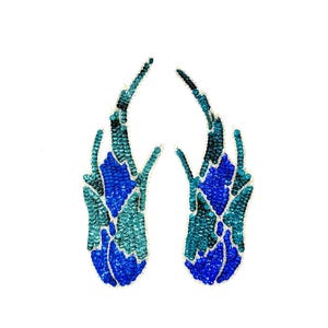 May include: Two matching, abstract, sequined appliques in shades of blue and teal. The appliques have a flame-like shape, with a central section of bright blue sequins and teal sequined edges. The background is plain white.