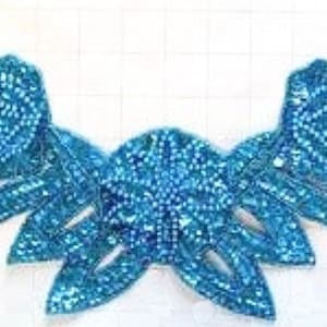 May include: A turquoise blue sequined applique with a floral design. The applique is made of small, iridescent sequins that are sewn together in a pattern of leaves and flowers. The applique is perfect for adding a touch of sparkle to any garment or craft project.