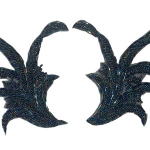 May include: A pair of symmetrical, dark navy blue beaded appliques featuring an intricate, organic leaf-like or feather-inspired design. Each piece is densely covered in small, reflective beads that create a textured, shimmering surface.
