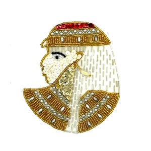 May include: An embroidered patch featuring a profile of an Egyptian pharaoh. The design incorporates gold, silver, and red beads, with white sequins and beads forming the face and headdress. The patch is likely for decorative purposes.