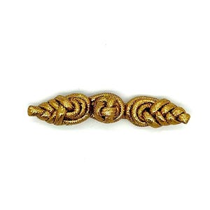 May include: A gold-colored decorative clasp with a knotted design. The clasp features three connected sections, with a central knot and two leaf-shaped ends. The clasp is set against a white background.
