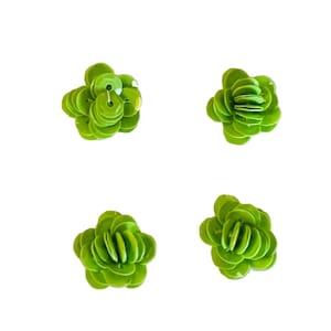 May include: Four lime green flower-shaped embellishments constructed from layered circular sequins. Each piece features a central hole and a stacked, dimensional design that mimics the appearance of a small, multi-petaled blossom.