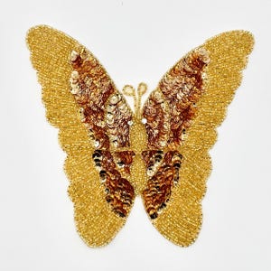 May include: A gold and brown beaded butterfly applique. The butterfly has a detailed design with sequins and beads.