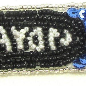 May include: Blue and black sequined iron-on patch with the word "Crayons" in white beads.