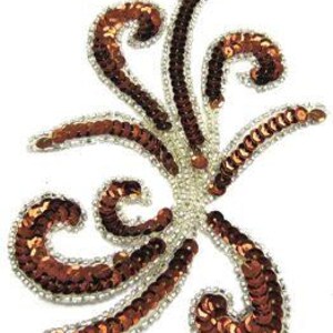 May include: A decorative applique with a swirling, floral design. The applique features copper-coloured sequins and a silver beaded border. The design is centered with a cluster of silver beads.