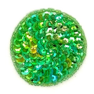 May include: A circular patch featuring vibrant green sequins layered in a dense, overlapping pattern. The edges are finished with a border of small, matching green seed beads, creating a textured, reflective surface that catches the light.