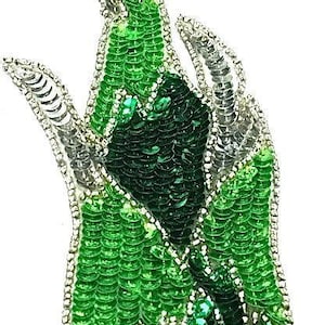 May include: Green and silver sequined applique in the shape of a flame. The applique is made of small, round sequins that are sewn together in a pattern. The applique is perfect for adding a touch of sparkle to any project.