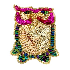 May include: An owl-shaped brooch crafted with vibrant sequins and beads. The design features bright pink sequins around the eyes, a central body of shimmering gold sequins, and wings outlined in iridescent green, blue, and purple sequins.