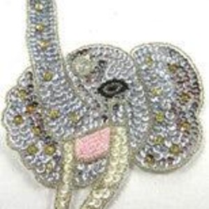 May include: A silver sequined elephant applique with pink and white accents. The elephant has a raised trunk and large ears.