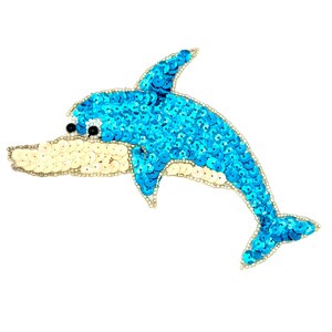 May include: A dolphin-shaped patch covered in bright blue sequins on the top and back, with a cream-colored sequin belly and snout. The eye is a small black bead, and the entire outline of the dolphin is bordered by tiny white seed beads.