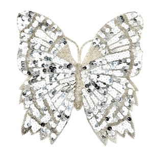 May include: A silver sequined butterfly applique. The butterfly is made of small, round sequins that are sewn together to create a shimmering effect.