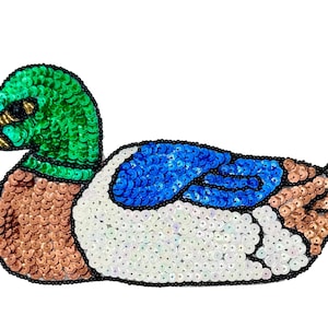 May include: A mallard duck patch crafted with vibrant sequins. The head is bright green, the beak is gold, the chest is light brown, the wing features a patch of blue, and the body is white with brown tail feathers, all outlined in black beads.