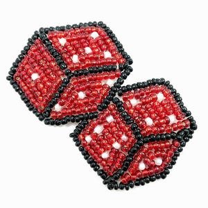 May include: Two red and black dice made of beads. The dice are in the shape of a cube and have white dots on each side.