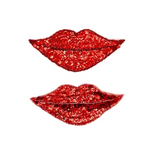 May include: Two red sequined lips patches on a white background. The lips are outlined with a darker red thread and filled with small, shiny sequins. The patches are identical in shape and size, ideal for embellishing clothing or accessories.