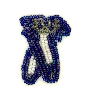May include: A beaded patch shaped like a pair of ballet slippers, constructed from iridescent dark blue and purple seed beads with white seed beads forming the ribbons and toe sections, creating a textured and reflective surface appearance.