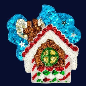 Peut inclure: Un écusson à paillettes en forme de maison en pain d'épices avec un toit marron, une bordure blanche et une fenêtre circulaire verte. La maison présente des murs rayés rouges et blancs avec des accents verts et rouges sur des nuages bleus.