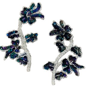 May include: Two floral-shaped appliqués featuring iridescent dark blue and green sequins. The stems and leaf outlines are constructed from clear, translucent seed beads, creating a structured botanical design with a reflective, shimmering finish.