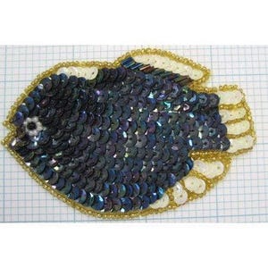 May include: A fish-shaped applique patch covered in iridescent dark blue and purple sequins. The fins and tail are accented with white sequins and outlined in gold beads. A small white beaded eye is visible on the head of the fish figure.