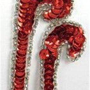 May include: Red sequined applique in the shape of a stylized letter 'J' with a silver trim.