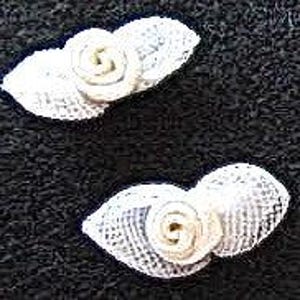 May include: Two white crocheted flower embellishments with a small white rose in the center of each.