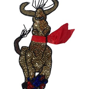 May include: A gold sequined bull with a red bandana around its neck and red, blue, and white sequined boots. The bull is standing on its hind legs with its front legs raised.