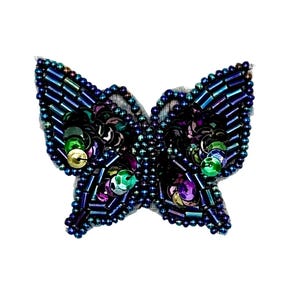 May include: A butterfly-shaped patch featuring iridescent dark blue, purple, and green sequins and beads. The wings are outlined with small dark blue beads and filled with a combination of cylindrical beads and round, reflective sequins in jewel tones.