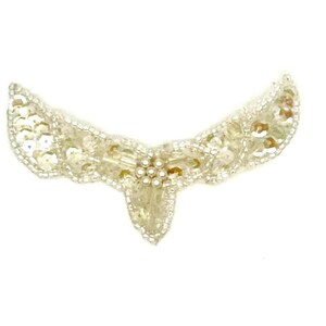 May include: A delicate, beaded applique in a crescent shape. The embellishment features clear sequins, beads, and small pearl accents. The design is symmetrical, with a central point and curved wings.