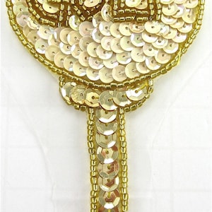 May include: A gold and white sequined iron-on patch with the word "GOLF" in the center. The patch is shaped like a golf club.