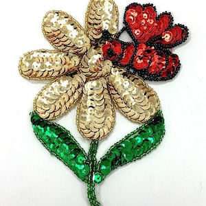 May include: A gold sequined flower with a red sequined butterfly on one petal and green sequined leaves. The flower is a decorative embellishment for clothing or crafts.