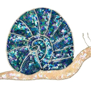 May include: A decorative snail patch featuring a shell covered in iridescent blue, green, and purple sequins. The body of the snail is crafted from light beige sequins, and the entire piece is outlined with small silver beads and two antennae.