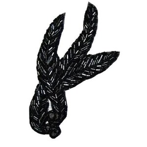 May include: Black beaded applique in a leaf design. The applique features a detailed pattern of small, shiny beads, creating a textured surface. The design includes three upward-curving leaf shapes and a rounded base, all in a dark, neutral color.
