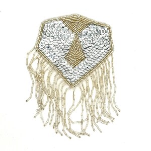 May include: A silver and gold beaded applique with a geometric design. The applique features silver sequins and gold beads, with beaded fringe hanging from the bottom. The item is likely for embellishing clothing or accessories.
