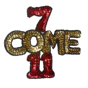 May include: A sequined patch with the words "COME 7 11" in gold and red sequins. The numbers and letters are outlined in black beads, creating a bold, eye-catching design. The patch is likely for clothing or accessories.