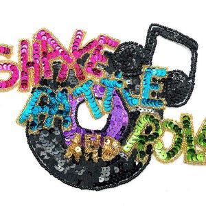 Peut inclure: Un écusson décoratif avec le texte SHAKE RATTLE AND ROLL en sequins multicolores. Les lettres sont bordées de fil doré, avec des sequins roses, bleus, violets, dorés et verts. Une note de musique en sequins noirs est intégrée au motif.