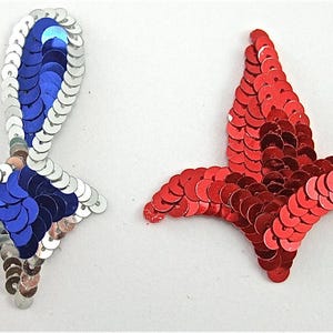 May include: Two sequined fabric appliques in the shape of birds. One bird is blue and silver, the other is red.