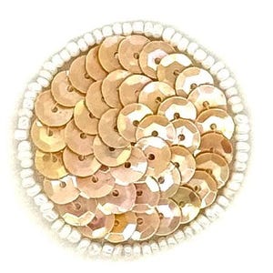 May include: A circular patch featuring a dense arrangement of overlapping metallic gold sequins in the center, surrounded by a single outer border of small, opaque white seed beads, creating a textured and reflective circular design element.