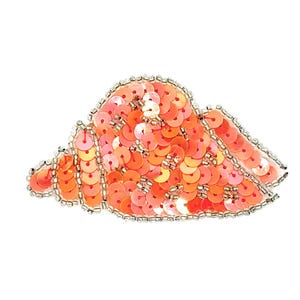 May include: A seashell-shaped patch embroidered with vibrant orange and coral sequins. The edges are outlined with small, metallic silver beads, creating a defined border around the shell's spiral structure and textured, shimmering surface.
