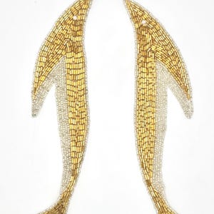 May include: A pair of elongated, curved appliques featuring gold-toned bugle beads arranged in a vertical pattern, bordered by a thin edge of small, clear white seed beads. The shapes are symmetrical and mirror each other in a slender, pointed design.